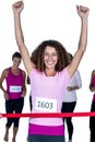 Portrait of smiling winner female athlete crossing finish line with arms raised Royalty Free Stock Photo