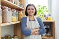 Portrait of a smiling woman in an apron in the kitchen in the pantry.