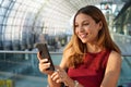 Portrait of smiling woman browsing on mobile phone in modern city station Royalty Free Stock Photo