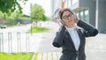 Portrait of a smiling woman in a business suit listening to music in headphones outdoors. Female office employee holds Royalty Free Stock Photo
