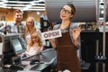 Portrait of smiling woman cashier holding open sign