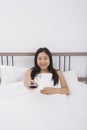 Portrait of smiling woman changing channels with remote control in bed Royalty Free Stock Photo