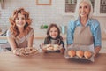 Portrait of smiling woman, daughter and grandmother holding freshly baked products and looking at the camera