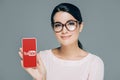 portrait of smiling woman in eyeglasses showing smartphone with youtube website on screen