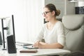 Portrait of smiling young woman in eyeglasses working in office and using graphic tablet Royalty Free Stock Photo