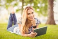 Portrait of smiling woman with hand on chin and holding digital tablet at park Royalty Free Stock Photo