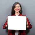 Portrait of smiling woman holding blank sign board.Studio portrait of young woman with sign card against gray background Royalty Free Stock Photo