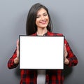 Portrait of smiling woman holding blank sign board.Studio portrait of young woman with sign card against gray background Royalty Free Stock Photo