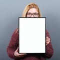 Portrait of smiling woman holding blank sign board.Studio portrait of young woman with sign card against gray background Royalty Free Stock Photo