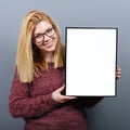 Portrait of smiling woman holding blank sign board.Studio portrait of young woman with sign card against gray background Royalty Free Stock Photo