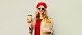 Portrait of smiling woman holding coffee cup and grocery shopping paper bag with long white bread baguette Royalty Free Stock Photo