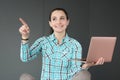 Portrait of smiling woman holding laptop and pointing her finger to side Royalty Free Stock Photo