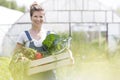 Portrait of smiling woman holding vegetables in crate at farm Royalty Free Stock Photo