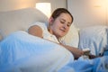 Portrait of smiling young woman lying in bed and reading book on digital tablet before going to sleep Royalty Free Stock Photo