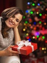 Portrait of smiling woman near christmas tree holding present box Royalty Free Stock Photo