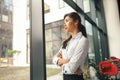 Portrait of smiling woman office worker standing with crossed hands in office and looking at side Royalty Free Stock Photo