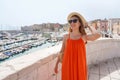 Portrait of smiling woman with orange dress walking in Bisceglie old town, Apulia, Italy