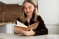 Portrait of Smiling woman reading personal diary in the kitchen Royalty Free Stock Photo