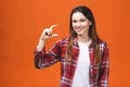 Portrait of smiling woman showing small amount of something, isolated against orange background Royalty Free Stock Photo