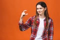 Portrait of smiling woman showing small amount of something, isolated against orange background Royalty Free Stock Photo