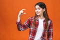 Portrait of smiling woman showing small amount of something, isolated against orange background Royalty Free Stock Photo