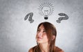 Portrait of smiling woman thinking with interogation point and bulb Royalty Free Stock Photo