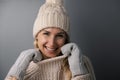 Portrait of smiling woman in warm winter clothing on gray background. knitted wool clothes