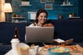 Portrait of smiling woman watching online television sitcom on laptop eating a home delivery burger