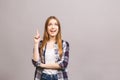 Portrait of a smiling woman pointing finger up at copy space isolated over gray background Royalty Free Stock Photo