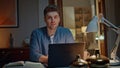 Portrait smiling worker posing at night home table closeup. Guy working laptop Royalty Free Stock Photo