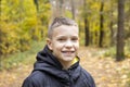 Portrait of a smiling 10-year-old boy in a jacket against the background of an autumn yellow forest. Concept: autumn holidays, goi