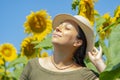 Portrait of a smiling 40-year-old woman in a straw hat against a background of blooming sunflowers. Photo shoot against the backgr