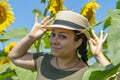 Portrait of a smiling 40-year-old woman in a straw hat against a background of blooming sunflowers. Photo shoot against the backgr