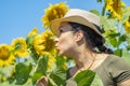 Portrait of a smiling 40-year-old woman in a straw hat against a background of blooming sunflowers. Photo shoot against the backgr