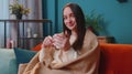 Portrait of smiling young adult woman in warm white sweater drink hot beverage mug relaxing at home Royalty Free Stock Photo