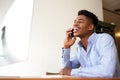 Smiling young african american businessman talking on phone while looking at computer Royalty Free Stock Photo