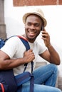 Smiling young african american man with bag talking with mobile phone Royalty Free Stock Photo
