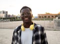 Portrait of a smiling young african american man with headphones looking at camera in a city Royalty Free Stock Photo