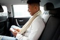 Smiling young african american man looking at cellphone while in backseat of car Royalty Free Stock Photo