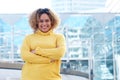 Smiling young african american woman with curly hair and arms crossed in city Royalty Free Stock Photo