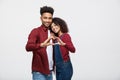 Portrait of a smiling young african couple dressed in casual clothes hugging and showing heart gesture with fingers Royalty Free Stock Photo