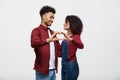 Portrait of a smiling young african couple dressed in casual clothes hugging and showing heart gesture with fingers Royalty Free Stock Photo