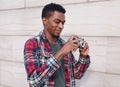 Portrait smiling young african man photographer with vintage film camera on city street over gray wall Royalty Free Stock Photo