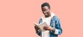 Portrait of smiling young african man student with book wearing eyeglasses isolated on pink background Royalty Free Stock Photo