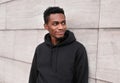 Portrait smiling young african man wearing black hoodie on city street over gray wall Royalty Free Stock Photo