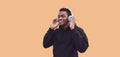 Portrait of smiling young african runner man in wireless headphones enjoying listening to music wearing black hoodie isolated on Royalty Free Stock Photo