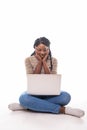 Portrait of smiling young afro american woman using laptop while sitting on a floor with legs crossed isolated over white Royalty Free Stock Photo