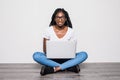 Portrait of young afro american woman using laptop while sitting on a floor with legs crossed  over white background Royalty Free Stock Photo