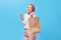 Portrait of a smiling young arabian college student showing shopping bags isolated on blue background