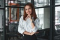 Portrait of smiling young Asian businesswoman standing in office. Thinking and thoughtful business concept. Royalty Free Stock Photo